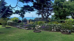 A garden with various trees and a view of the sea. - Luxury Beach House on two acres / Private Bathing Box / Botanic Like Gardens (Dromana)