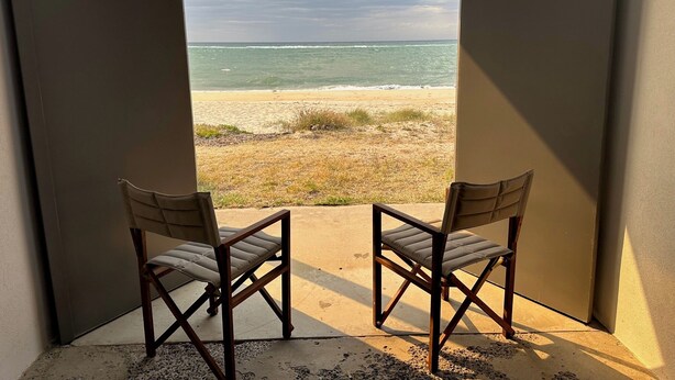 A room with two chairs facing a beach view through an open doorway. - Luxury Beach House on two acres / Private Bathing Box / Botanic Like Gardens (Dromana)