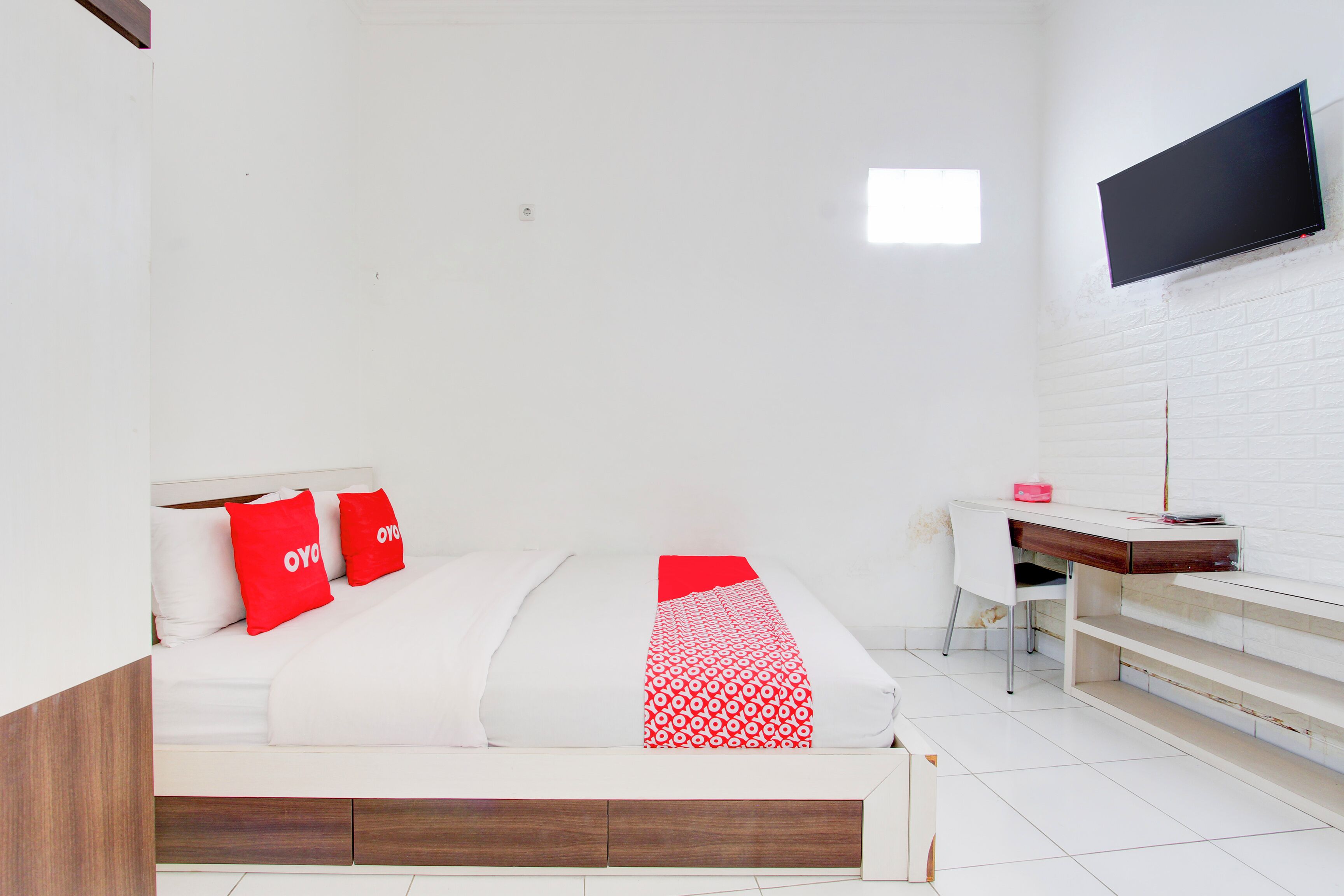 Una camera d'albergo moderna con un letto, una scrivania e una TV a parete.