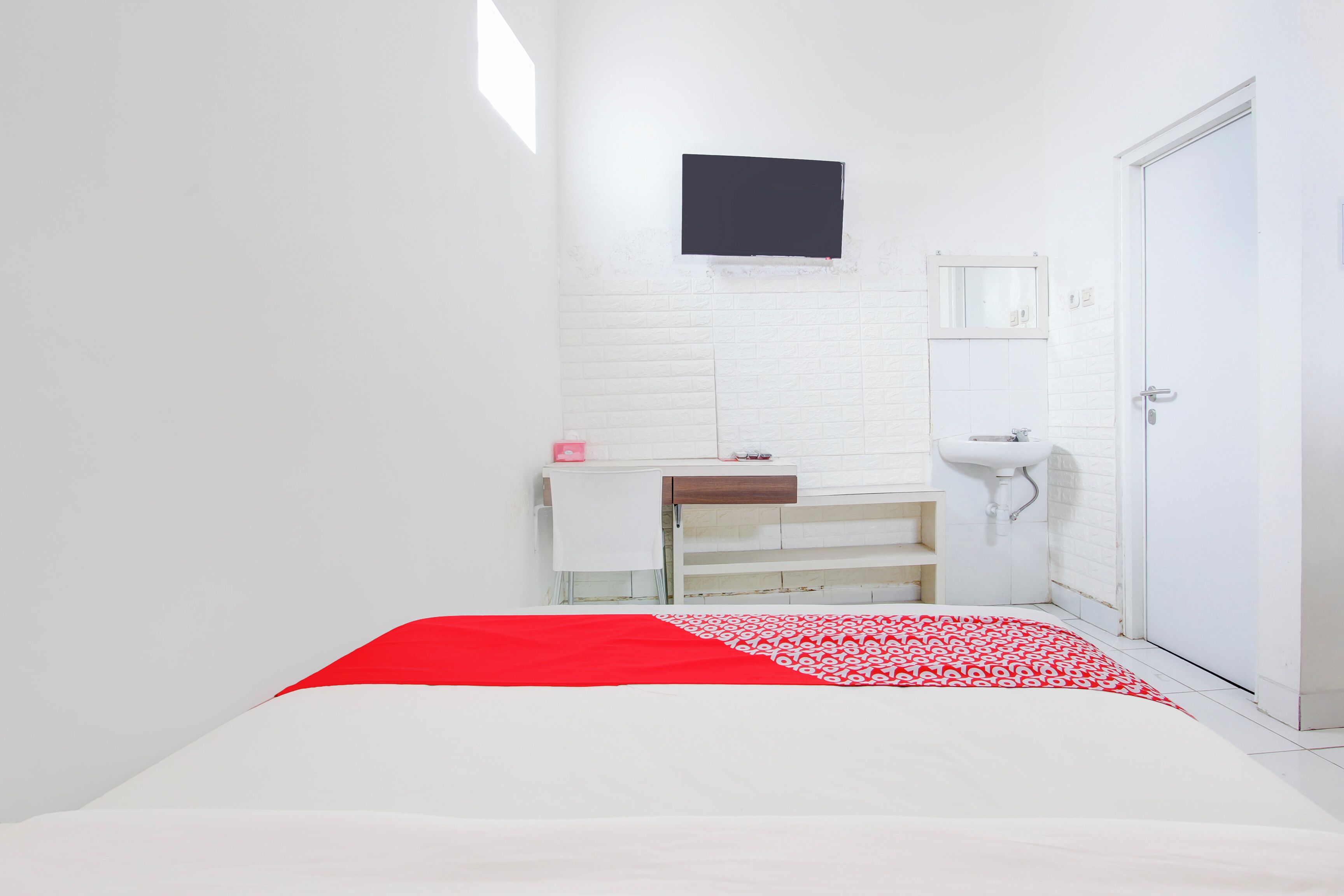 A small, bright room with a bed, a white sink, and a white wardrobe.