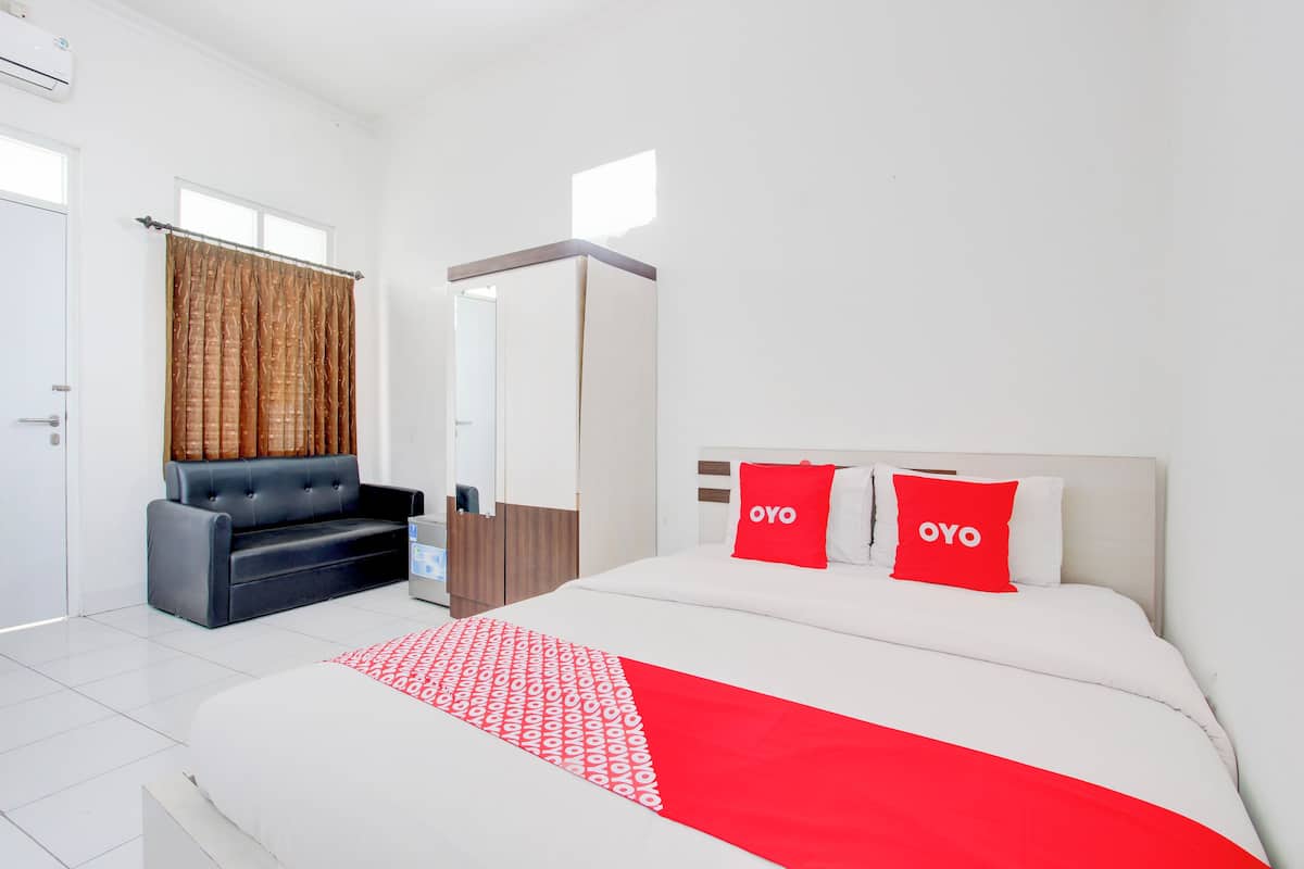 Een hotelkamer met een bed, een bank, een garderobe en een spiegel.
