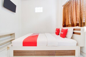 A neatly made bed with white and red bedding, a wooden headboard, and a window with curtains. - Hotel O near Plaza Ambarrukmo Yogyakarta formerly Wisma Arya 2 (Banguntapan)