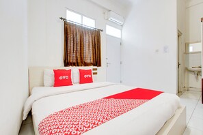 A hotel room with a bed, a window with curtains, a white sink, and a mirror. - Hotel O near Plaza Ambarrukmo Yogyakarta formerly Wisma Arya 2 (Banguntapan)