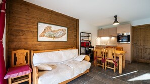 Een gezellige kamer met een houten bank, een eettafel met stoelen, een keuken met apparatuur en een kaart aan de muur.
