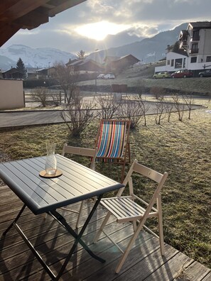 A patio with a table and chairs, a view of a snowy mountain, and a building with balconies. - Beautiful, bright apartment for 6 pers (Morillon)