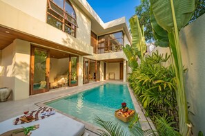 A modern house with a swimming pool, large windows, and tropical plants. - Akela Villas Bingin (Pecatu)