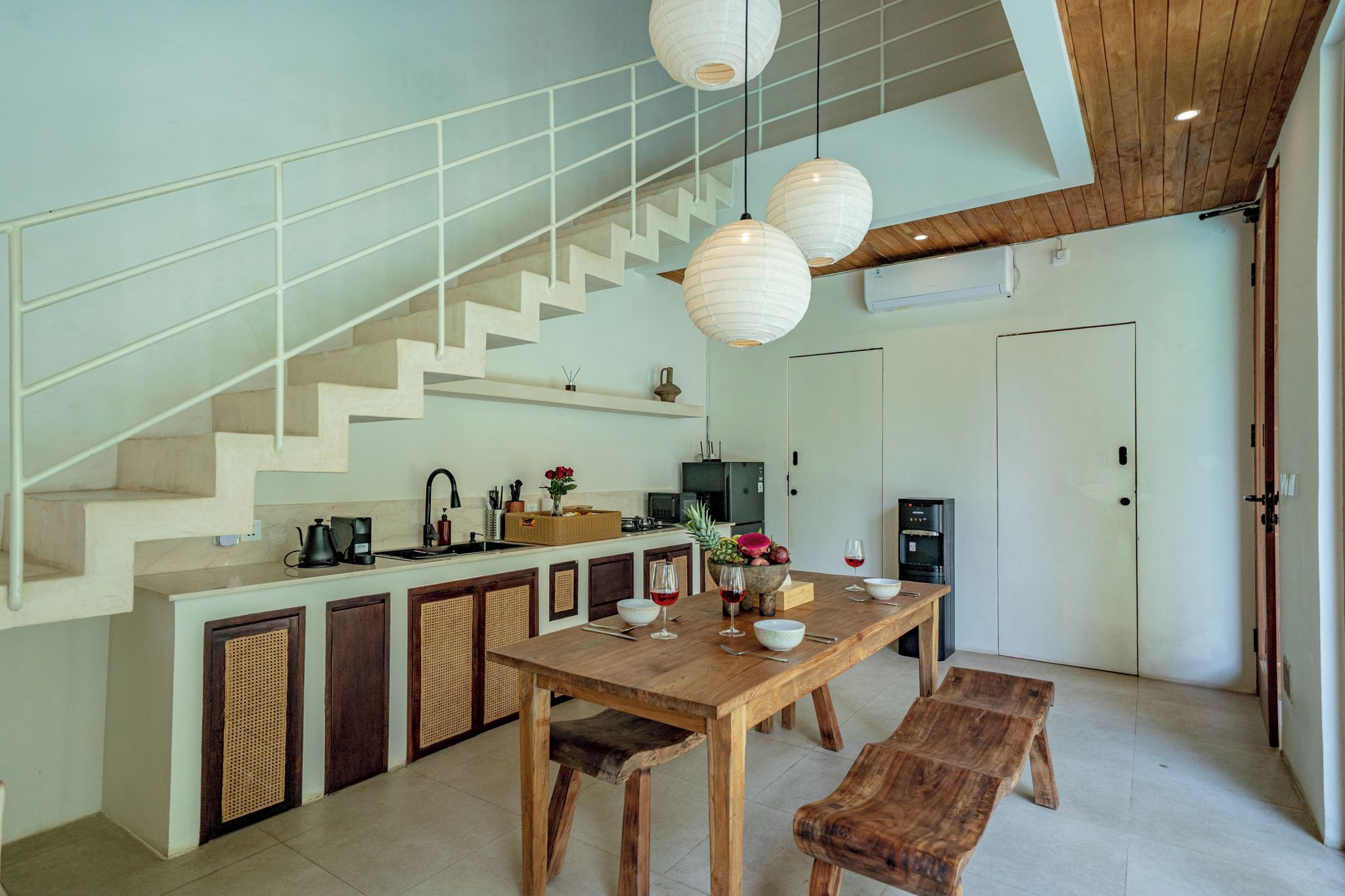 A modern kitchen with a wooden dining table, built-in cabinets, and a staircase.