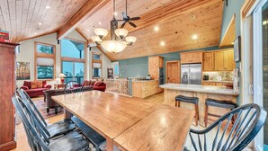 Une cuisine spacieuse dotée de meubles en bois, d’un grand îlot central et d’un coin repas avec une table et des chaises en bois.