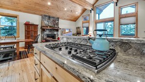 Une cuisine spacieuse dotée d’un plan de travail en granit, d’une cuisinière à gaz et de meubles de rangement en bois.