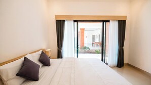 A hotel room with a large bed, a wooden headboard, and a view of the outside through a glass door. - Kubu Dangin Guest House Kerobokan  (Keroboken Kelod)
