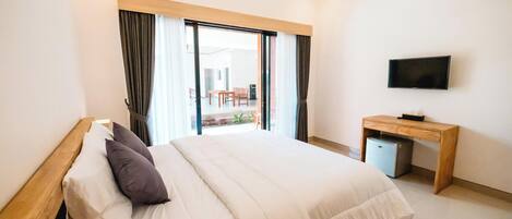 A hotel room with a bed, a desk, a television, and a view of the outside.