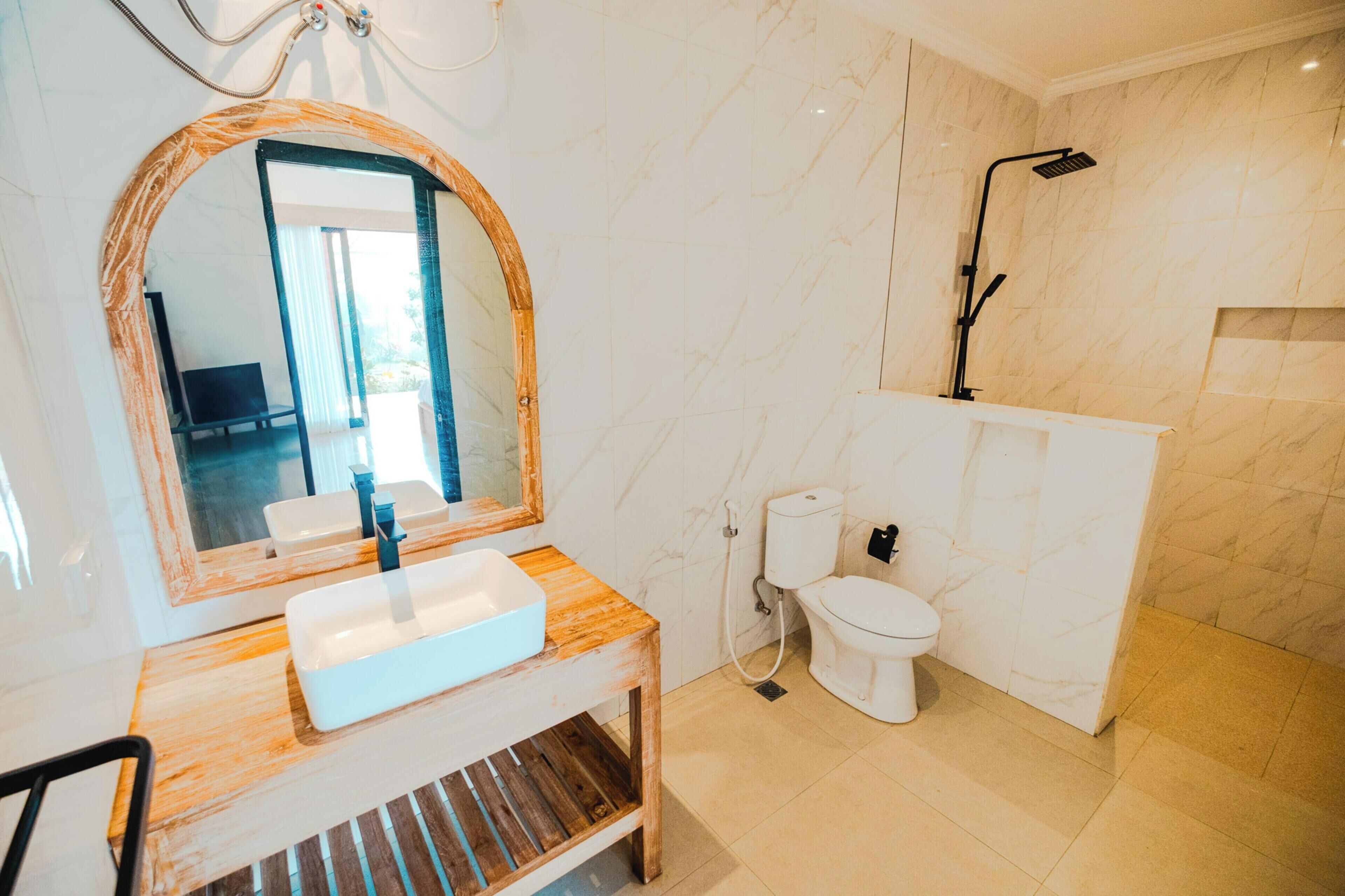 Un baño con tocador de madera, un espejo grande, inodoro y ducha.