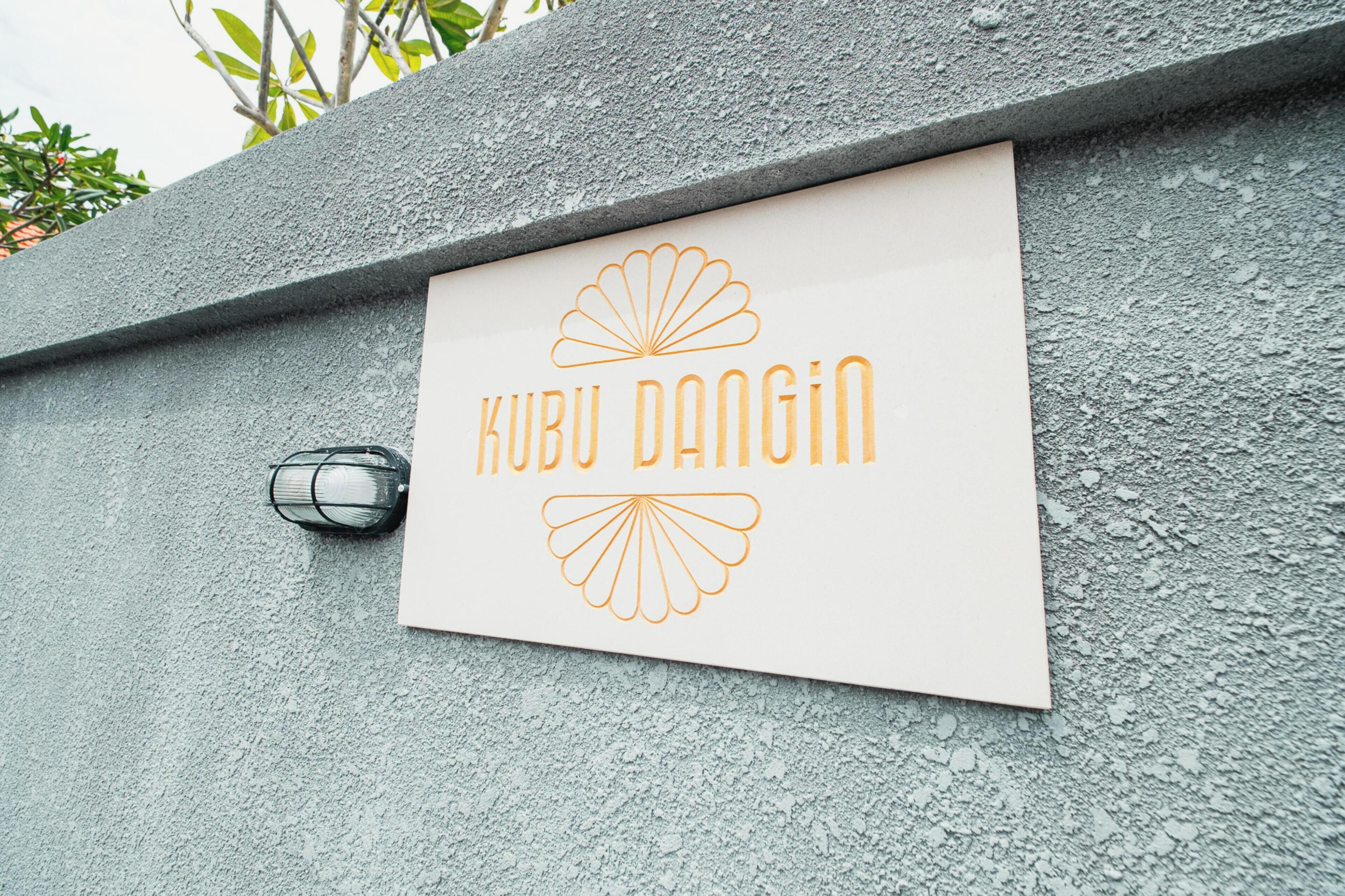 A sign with the text "Kubu Dangin" on a textured wall.