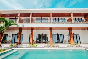 Un hotel con piscina, varios balcones y zonas de estar al aire libre.