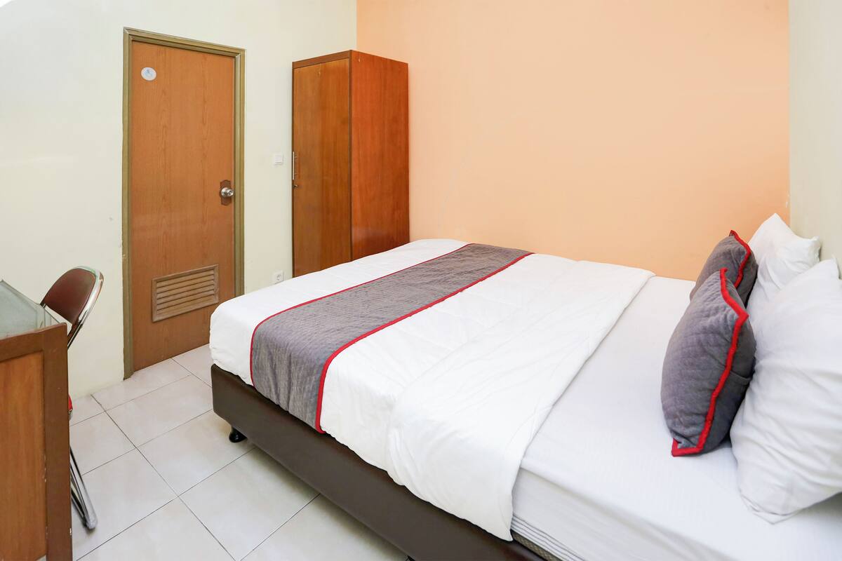 A neatly arranged hotel room with a bed, a desk, and a wardrobe.