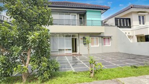 A two-story residential building with a tiled patio, a balcony, and a small garden area. - Hotel O Tangerang Near Supermall Karawaci  Formerly Bromo 18 (Curug)