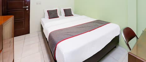 A neatly made bed with a white and gray bedspread, two pillows, and a wooden headboard.