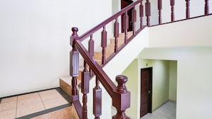 A wooden staircase with a handrail and balusters, leading to a landing with a door. - Hotel O Tangerang Near Supermall Karawaci  Formerly Bromo 18 (Curug)