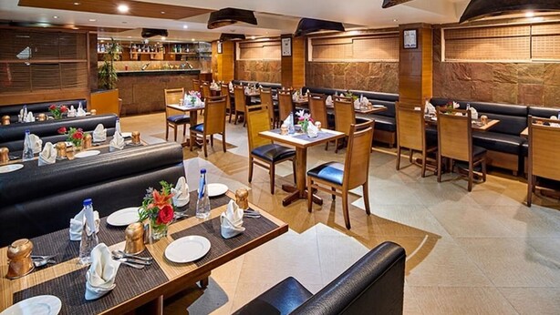 A restaurant with booths and tables, some with water bottles and napkins. - Coral Tree (Bengaluru)