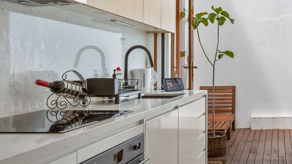 Een moderne keuken met een wijnfles, koffiezetapparaat en een tablet op het aanrecht.