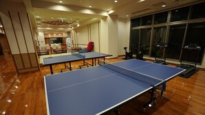 Ett rum med två bordtennisbord, en röd stol och motionscyklar.