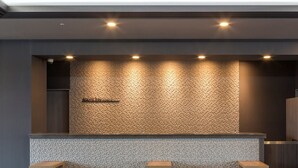 A reception area with a textured wall, a tiled counter, and three wooden stools.