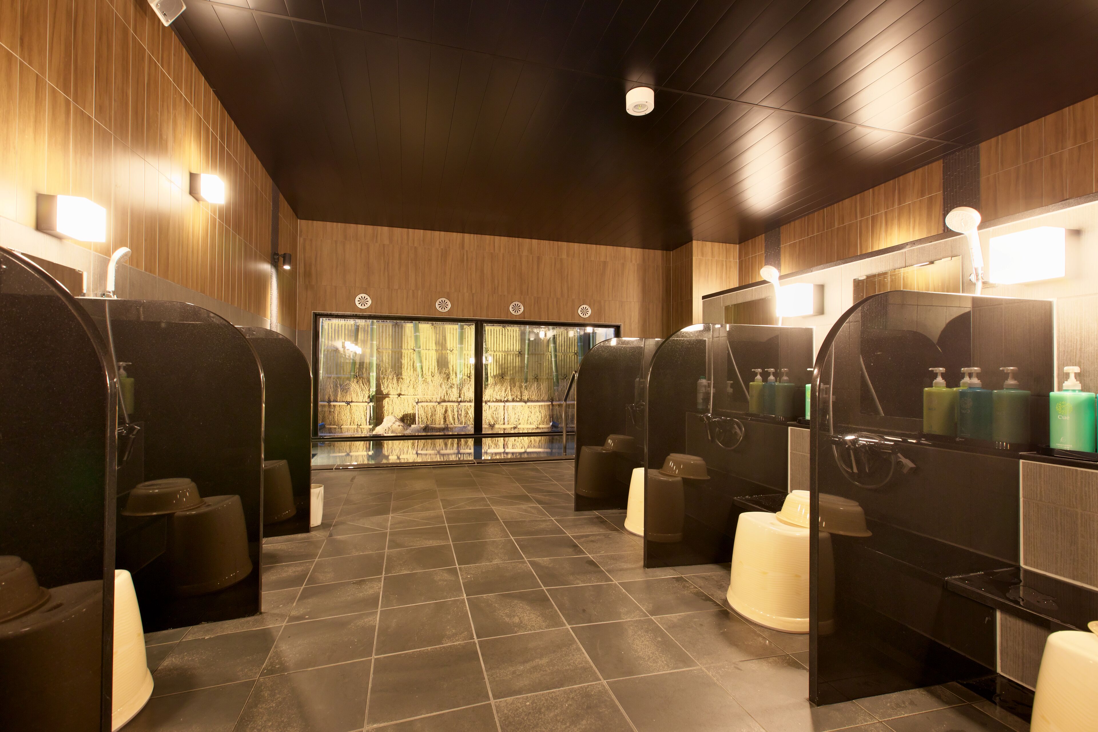 Un baño moderno con varios cabina de ducha, cada una con espejo y dispensador de jabón.