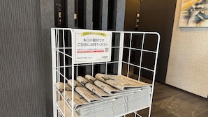 A metal rack holding newspapers with a sign above it.