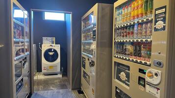 Une laverie équipée de plusieurs machines à laver et de distributeurs automatiques de boissons et d’en-cas.