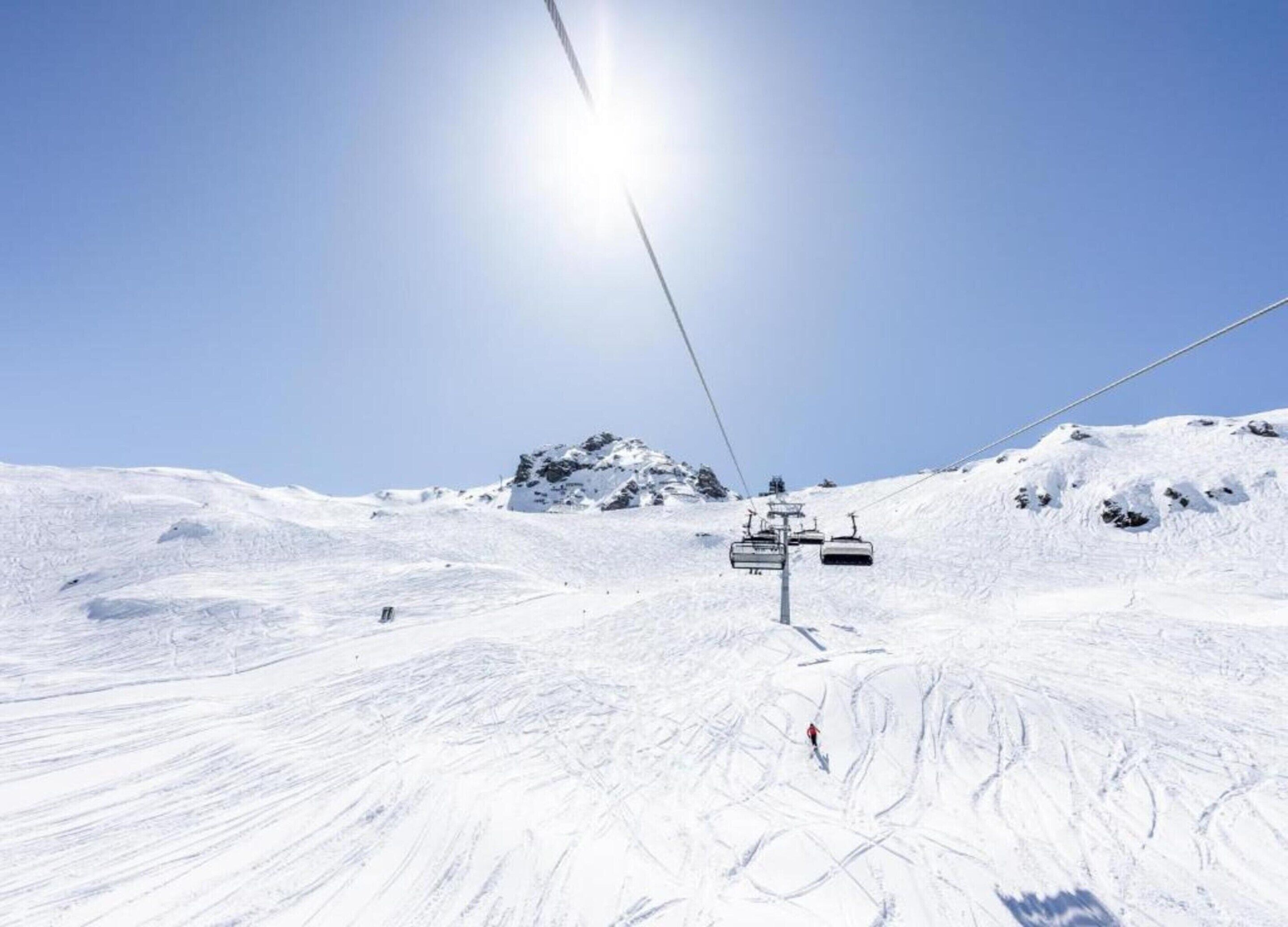 A ski lift on a snowy mountain slope with a clear sky.