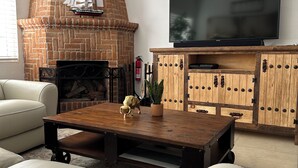 Un soggiorno con camino in mattoni, televisore a schermo piatto e mobile TV in legno.