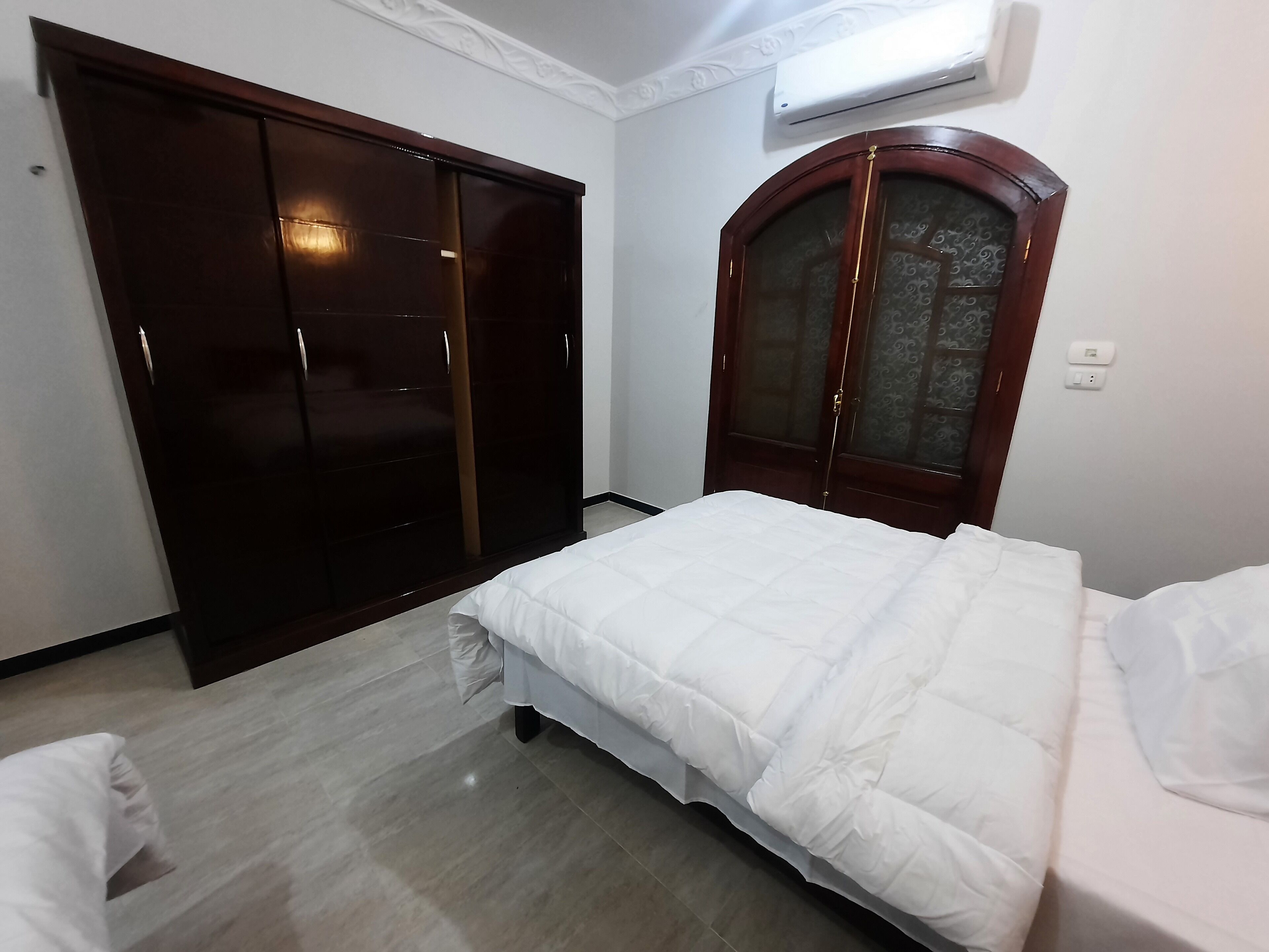 A bedroom with a bed, a wardrobe, and a door with a glass panel.