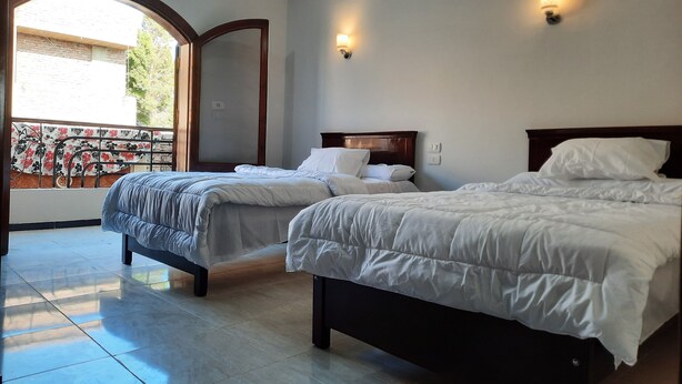 A hotel room with two beds, a balcony with a decorative railing, and a large mirror. - Charming 2-bedroom apartment with WiFi, AC in wonderful Luxor Governorate . (Luxor Governorate)