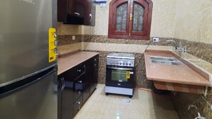 A compact kitchen with a refrigerator, stove, sink, and cabinets. - Charming 2-bedroom apartment with WiFi, AC in wonderful Luxor Governorate . (Luxor Governorate)
