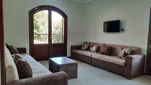 A living room with a sofa set, a coffee table, and a TV mounted on the wall. - Charming 2-bedroom apartment with WiFi, AC in wonderful Luxor Governorate . (Luxor Governorate)