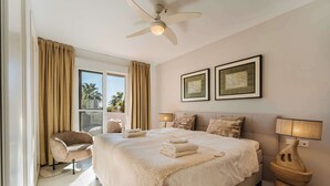 A hotel room with a large bed, a chair, two bedside lamps, and a ceiling fan. - Locrimar | Terrace Pool View Padel Gym Apartment (Marbella)