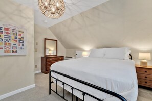Une chambre à coucher avec un grand lit, une commode, un miroir et un lustre.