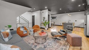 Un salon moderne avec un escalier, un coin repas et une cuisine.