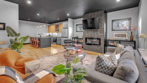 Un salon moderne avec une cheminée, un canapé, une table basse et un coin repas à l’arrière-plan.