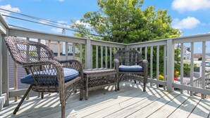 A wooden deck with wicker chairs and a white railing.