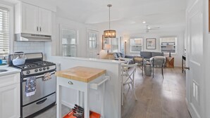 A modern kitchen with white cabinetry, a gas stove, and a wooden countertop.