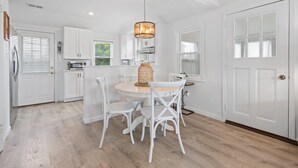 A bright kitchen with white cabinetry, a round dining table, and white chairs.