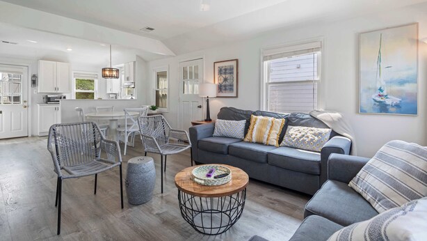 A spacious living area with a gray sofa, a round coffee table, and wicker chairs.