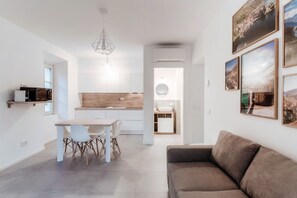 A modern kitchen with white cabinets, a wooden countertop, and a dining area with a table and chairs.