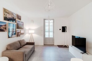 A modern living room with a sofa, a television, a floor lamp, and framed pictures on the wall. - Marinetti Suite 9 - MyHomeinComo (Como)