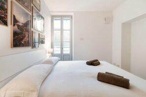 A bedroom with a bed, a window, and wall-mounted artwork.