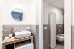 A modern bathroom with a freestanding sink, a mirror, and a toilet. - Marinetti Suite 9 - MyHomeinComo (Como)