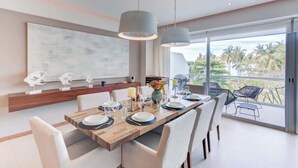 A modern dining area with a wooden table, white chairs, and pendant lighting.