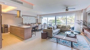 A modern living room with a sofa, coffee table, and a dining area with chairs.