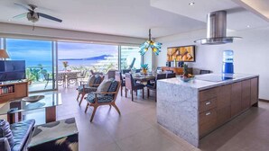 A modern living room with a glass coffee table, a sofa, and a dining area with chairs and a table. - Peninsula Deluxe Resort, 4 BR, Great Ocean Views, Great amenities (Flamingos)